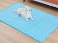 Small white dog resting on a blue quilted ice silk cooling mat laid flat on a wood floor