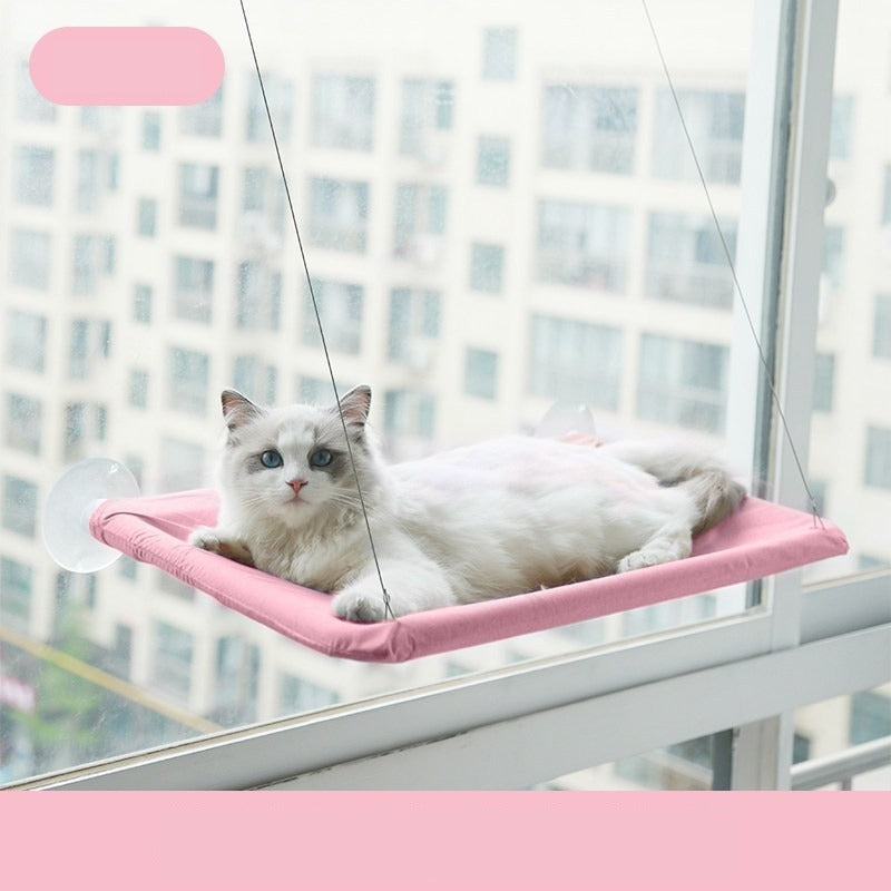 Pink suction cup cat window hammock mounted on apartment glass with a white cat resting on it